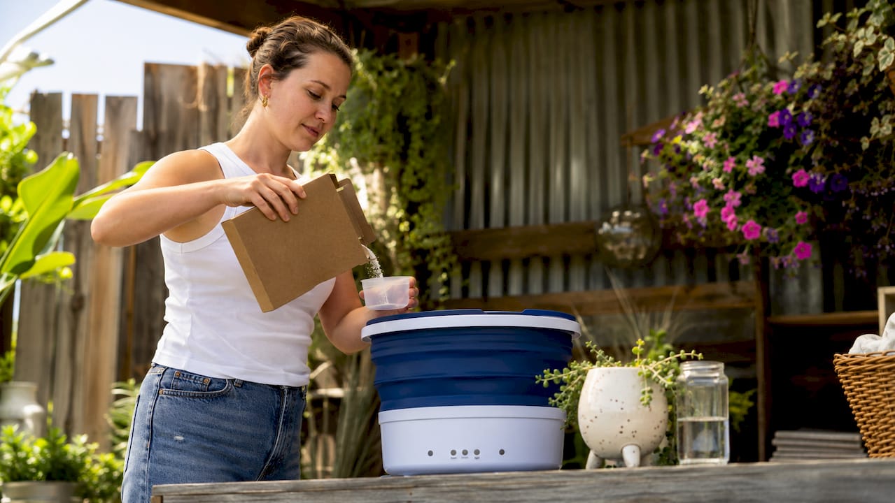 Woman pouring powder detergent in laundry room
